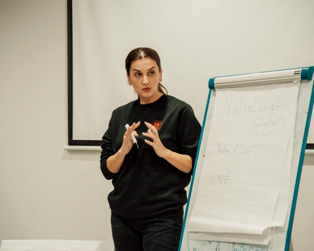 Woman confidently presenting with a flip chart in a classroom setting.